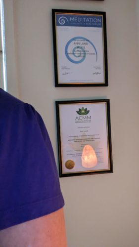 Shoulder of someone wearing purple for International Women's Day with certificates on wall behind