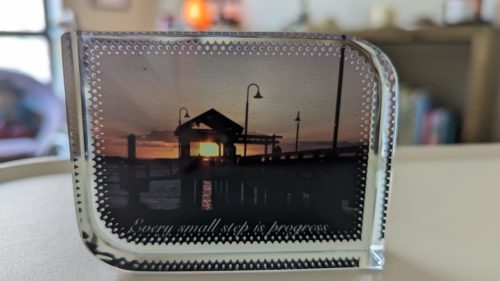 Paperweight showing a pier at sunset with the words  'Every samll step is progress'