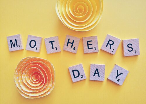 Scrabble letters spell out Mother's Day with two paper flowers