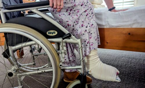 Person with bandaged foot getting out of wheelchair onto bed