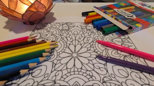coloured pens and pencils on a colouring in sheet
