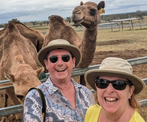 Man & woman laughing with two camels behind them